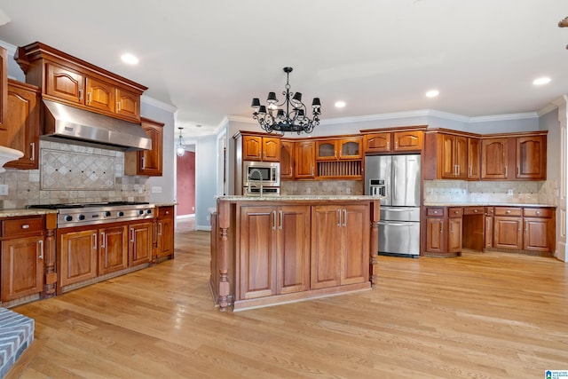 kitchen with range hood, stainless steel appliances, a notable chandelier, a center island with sink, and decorative light fixtures