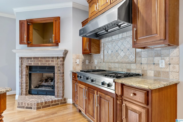 kitchen featuring ventilation hood, ornamental molding, stainless steel gas cooktop, and light stone counters