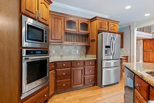 kitchen featuring crown molding, backsplash, stainless steel appliances, light stone counters, and light hardwood / wood-style floors