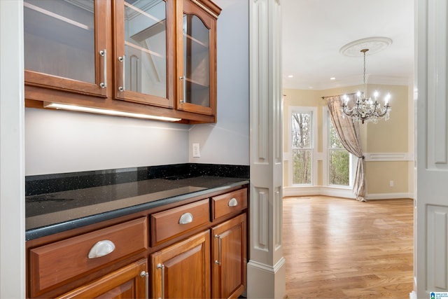 bar featuring decorative light fixtures, a chandelier, dark stone counters, light hardwood / wood-style floors, and crown molding