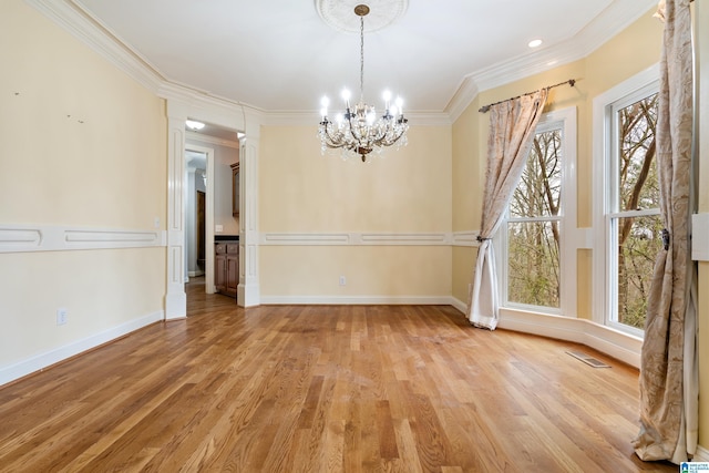 empty room featuring a notable chandelier, crown molding, and light hardwood / wood-style flooring