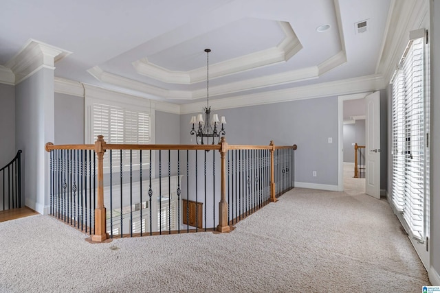 corridor with crown molding, carpet floors, a notable chandelier, and a tray ceiling