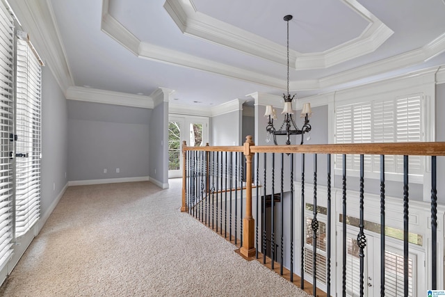 hallway featuring crown molding, carpet, an inviting chandelier, and a tray ceiling