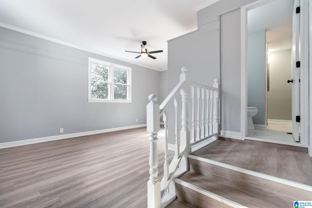 stairway featuring hardwood / wood-style floors, ornamental molding, and ceiling fan