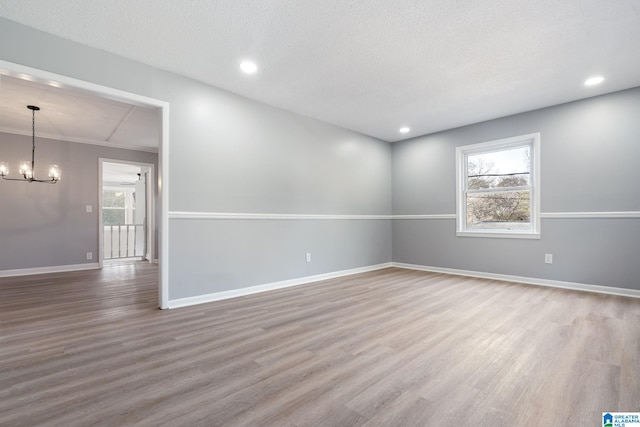 spare room with hardwood / wood-style floors, a textured ceiling, and a chandelier