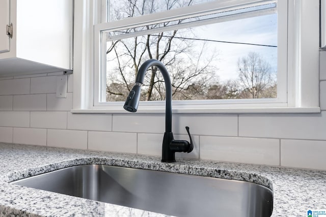 details with white cabinetry, light stone countertops, sink, and decorative backsplash