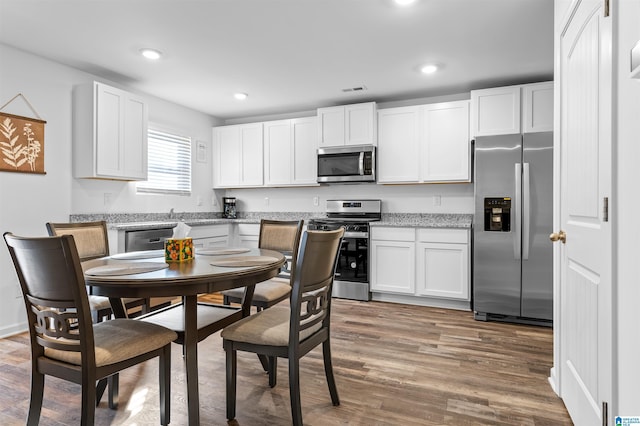 kitchen with hardwood / wood-style floors, white cabinets, and appliances with stainless steel finishes