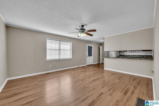 unfurnished living room with crown molding, light hardwood / wood-style floors, ceiling fan, and a textured ceiling