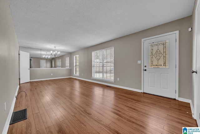 entrance foyer with wood-type flooring, a textured ceiling, and a notable chandelier