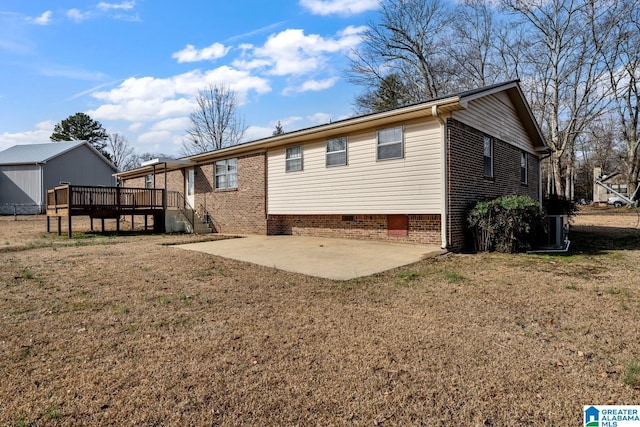 rear view of property featuring a wooden deck, a yard, and a patio area