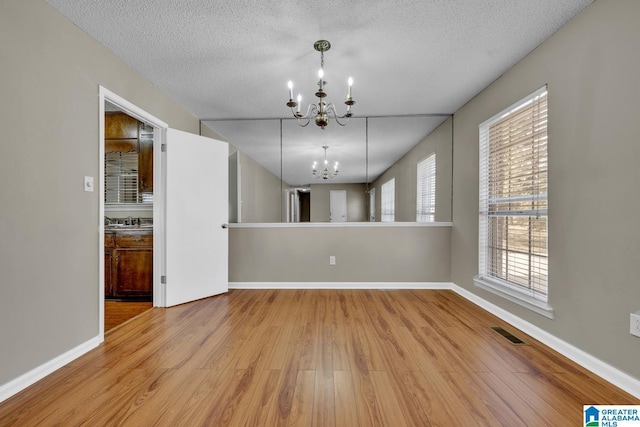 unfurnished dining area with light wood-type flooring, sink, a textured ceiling, and a chandelier