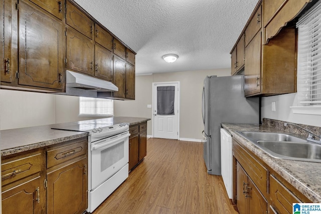 kitchen featuring sink, white appliances, a textured ceiling, and light wood-type flooring