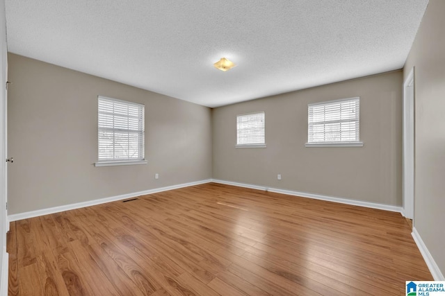 unfurnished room featuring a textured ceiling and light wood-type flooring