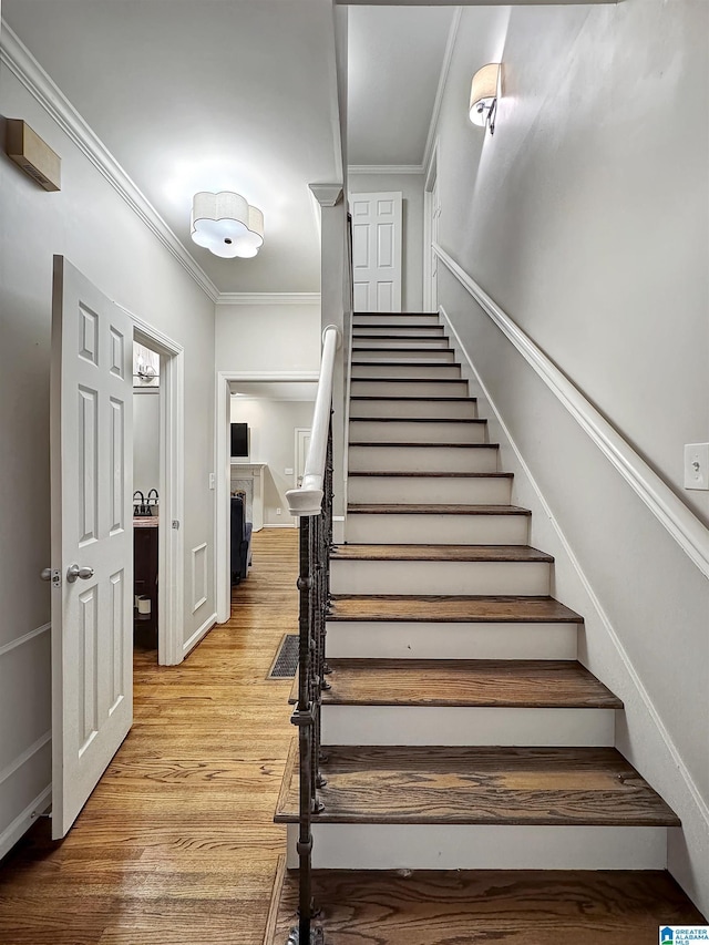 stairs with crown molding and hardwood / wood-style floors