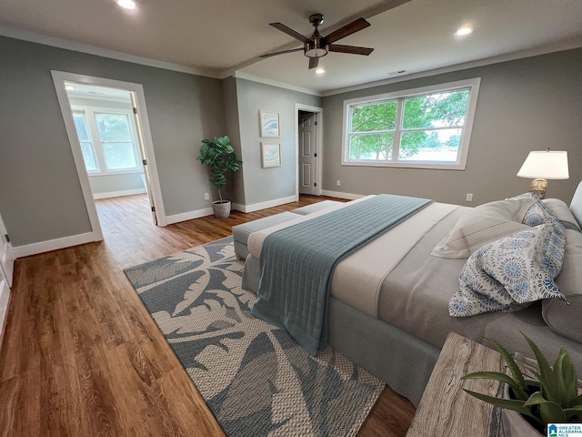 bedroom featuring crown molding, hardwood / wood-style flooring, multiple windows, and ceiling fan