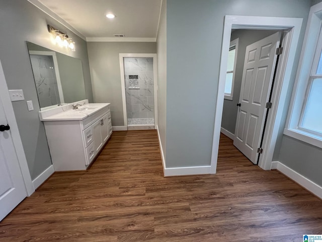 bathroom featuring vanity, hardwood / wood-style floors, crown molding, and tiled shower