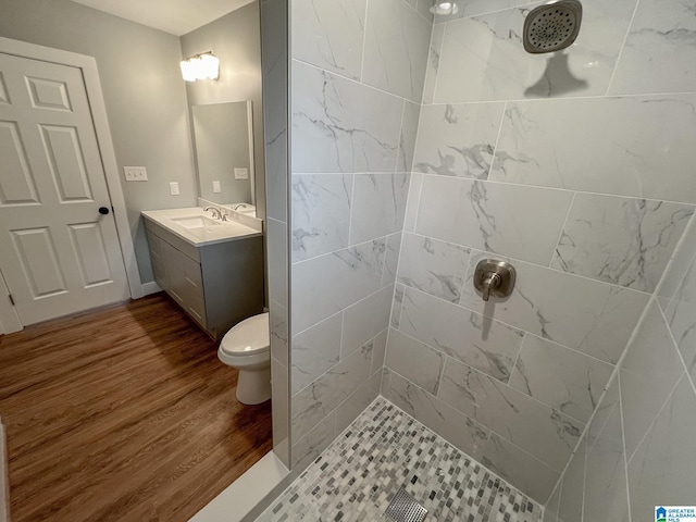 bathroom with vanity, toilet, hardwood / wood-style floors, and a tile shower