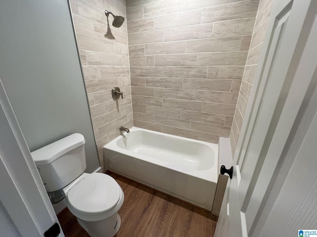 bathroom with hardwood / wood-style flooring, tiled shower / bath, and toilet