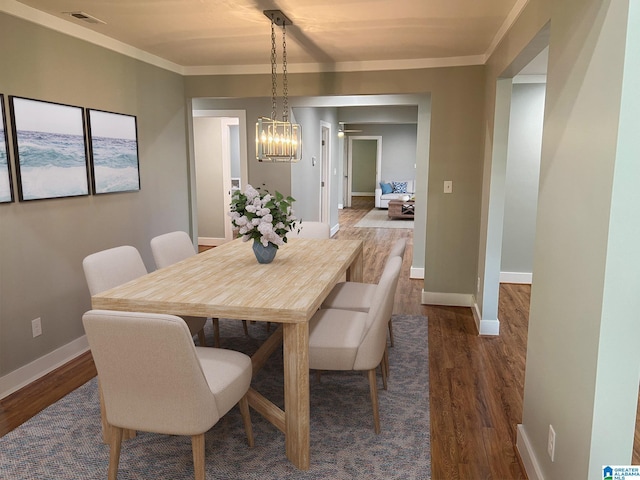 dining space with an inviting chandelier, crown molding, and dark hardwood / wood-style floors