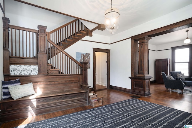 stairs featuring hardwood / wood-style floors, a notable chandelier, and ornate columns