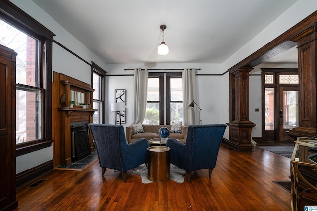 living room with dark hardwood / wood-style flooring, plenty of natural light, and ornate columns