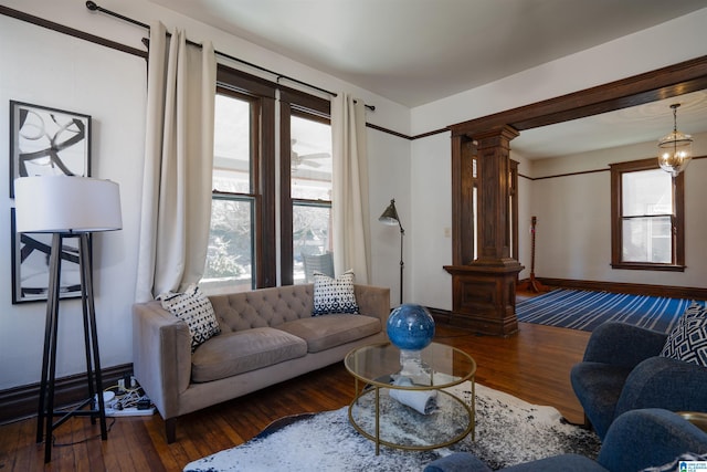 living room with dark wood-type flooring, a chandelier, and decorative columns