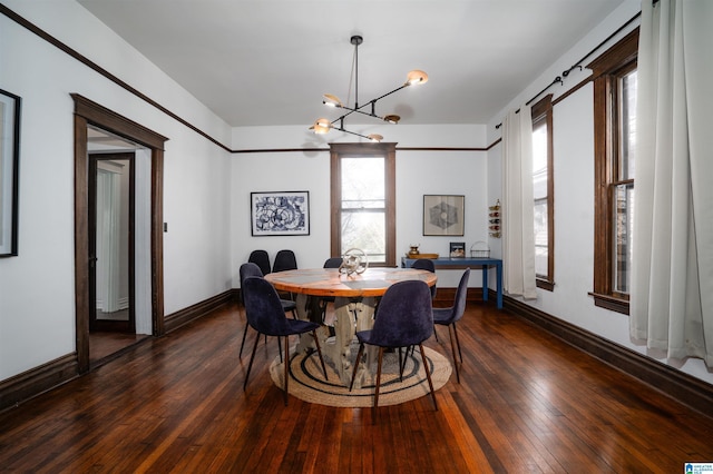 dining area featuring dark wood-type flooring and an inviting chandelier