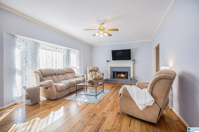 living room featuring crown molding, a brick fireplace, ceiling fan, and light hardwood / wood-style floors