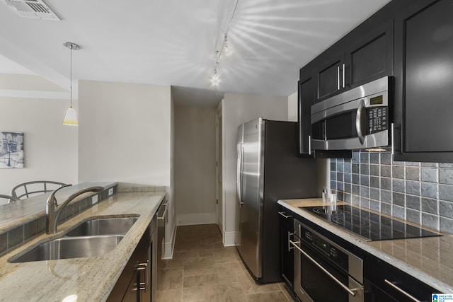 kitchen featuring sink, stainless steel appliances, light stone counters, decorative backsplash, and decorative light fixtures