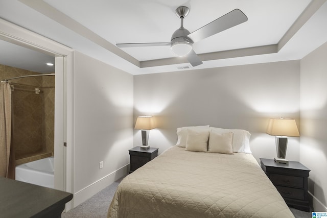 carpeted bedroom with a raised ceiling and ceiling fan