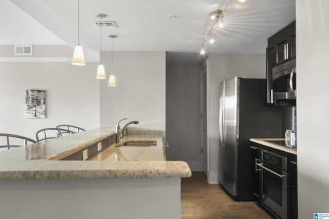 kitchen with appliances with stainless steel finishes, sink, hanging light fixtures, kitchen peninsula, and light stone countertops