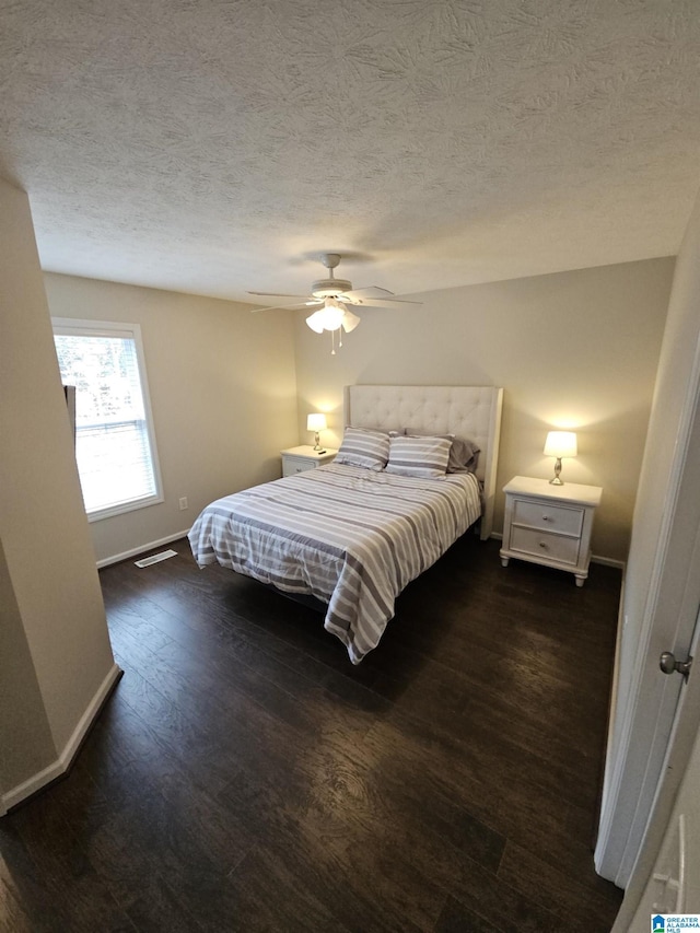 bedroom with ceiling fan, a textured ceiling, and dark hardwood / wood-style flooring