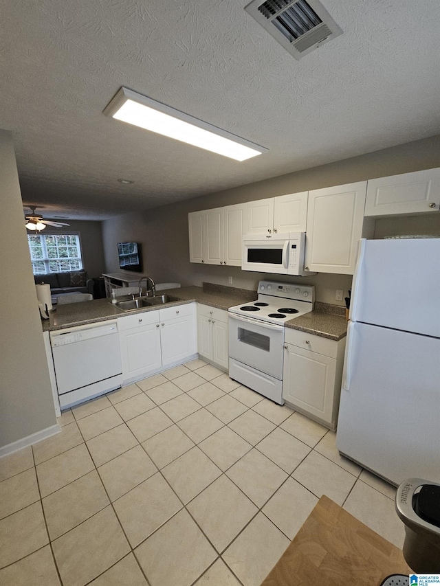 kitchen featuring sink, a textured ceiling, light tile patterned floors, white appliances, and white cabinets