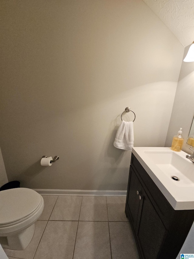 bathroom with lofted ceiling, vanity, toilet, tile patterned floors, and a textured ceiling