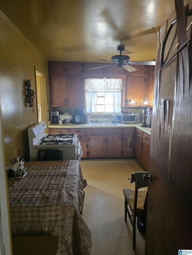 kitchen featuring sink, white range with gas stovetop, and ceiling fan