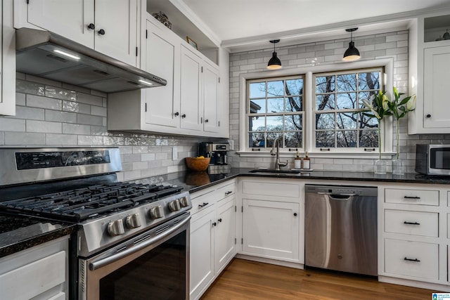 kitchen featuring decorative light fixtures, sink, white cabinets, dark stone counters, and stainless steel appliances