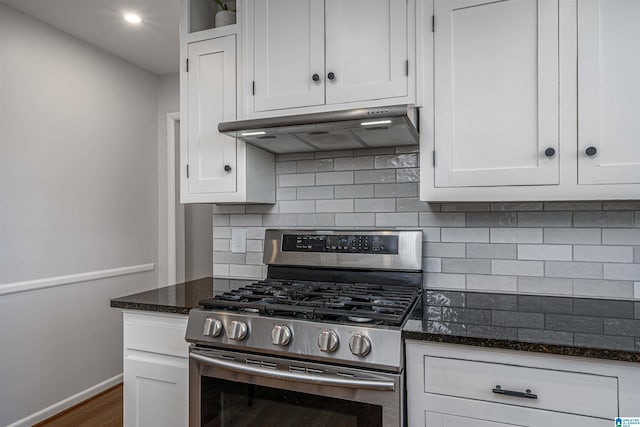 kitchen featuring dark wood-type flooring, white cabinetry, dark stone countertops, stainless steel range with gas stovetop, and backsplash