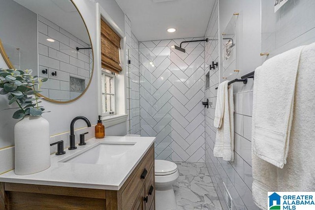 bathroom featuring tiled shower, vanity, and toilet