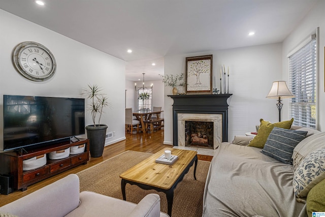 living room featuring a notable chandelier, wood-type flooring, and a premium fireplace