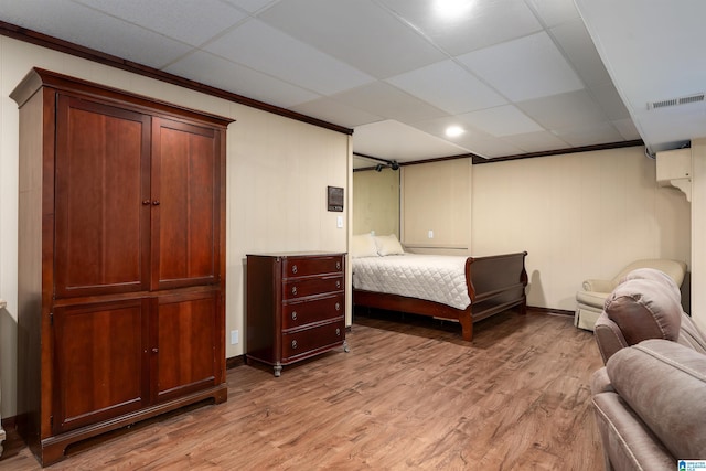 bedroom with a drop ceiling and light wood-type flooring