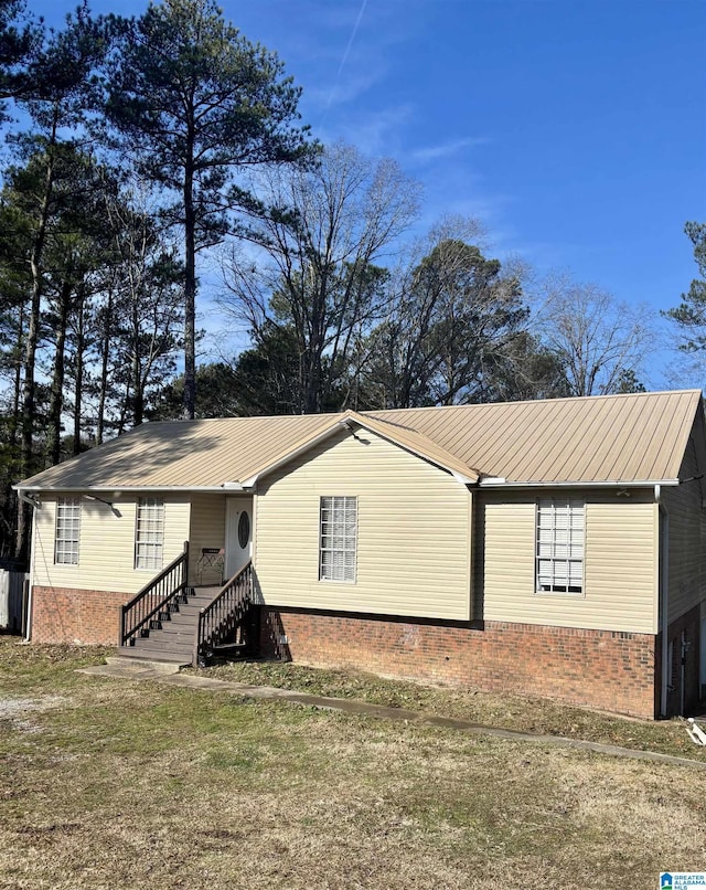 single story home with metal roof, brick siding, and a front yard