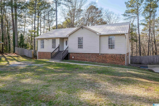 ranch-style home featuring metal roof, fence, a front lawn, and brick siding