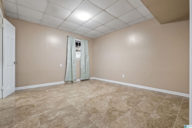 unfurnished room featuring a drop ceiling and baseboards