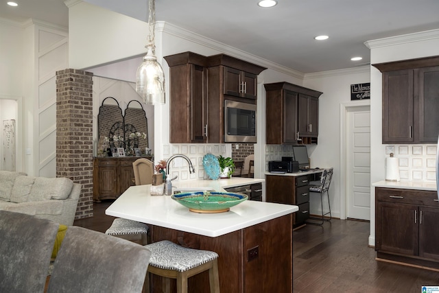 kitchen featuring dark wood-type flooring, stainless steel microwave, decorative light fixtures, and backsplash