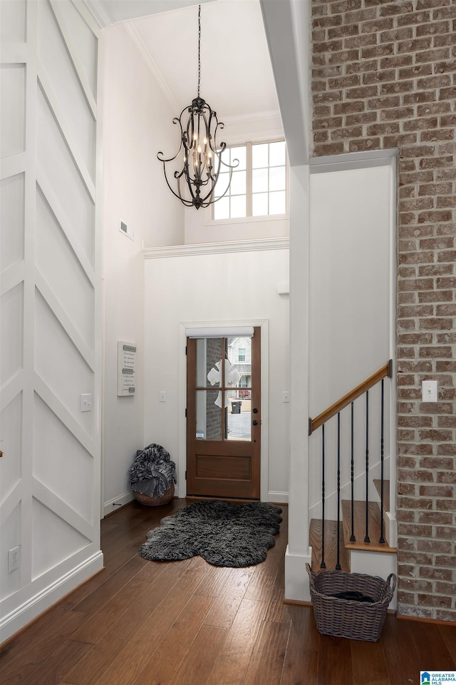 entrance foyer with a high ceiling, crown molding, a chandelier, and dark hardwood / wood-style flooring