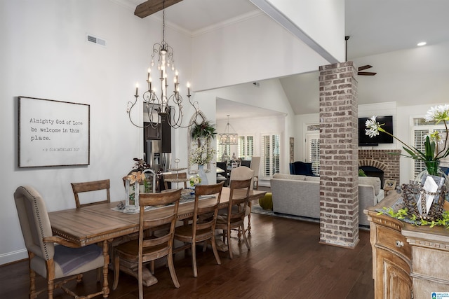 dining room featuring a brick fireplace, ornamental molding, dark hardwood / wood-style flooring, a towering ceiling, and ceiling fan with notable chandelier