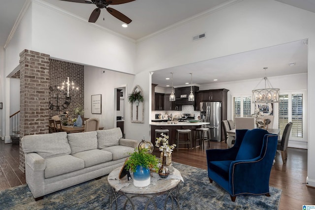 living room with a towering ceiling, ceiling fan with notable chandelier, ornamental molding, and dark hardwood / wood-style floors