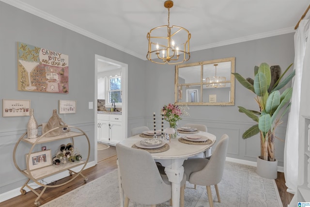 dining area featuring sink, crown molding, light hardwood / wood-style flooring, and a chandelier