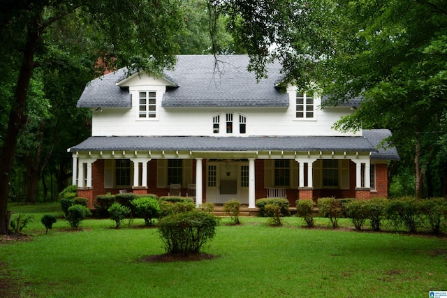 rear view of house featuring covered porch and a lawn