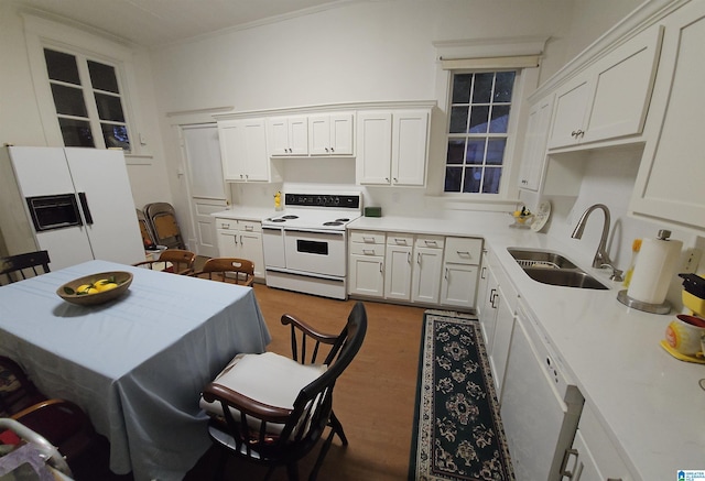 kitchen featuring sink, white cabinets, a kitchen bar, hardwood / wood-style flooring, and white appliances